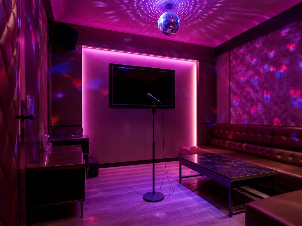 Privat karaoke-studio med neonbelysning, mikrofon på scen och discobollsreflektioner