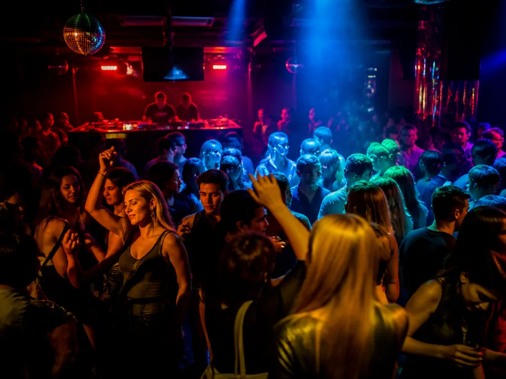 Livlig dansgolvsatmosfär på en nattklubb i Stockholm med färgglada ljus och dansande besökare